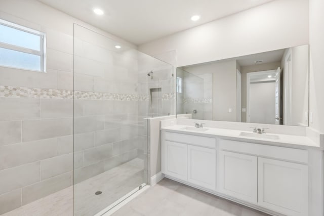 bathroom featuring double vanity, recessed lighting, a walk in shower, and a sink