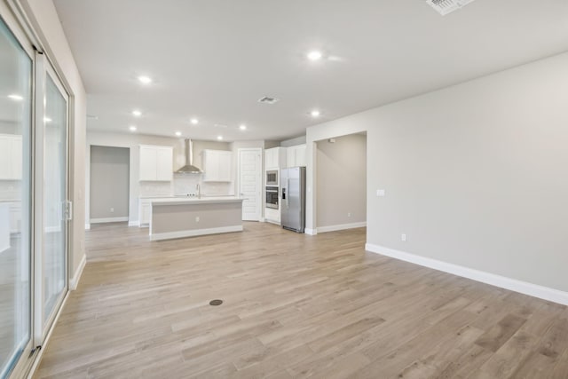 unfurnished living room featuring recessed lighting, light wood-type flooring, baseboards, and a sink