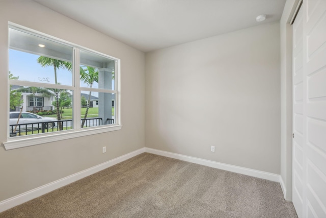 carpeted empty room featuring baseboards