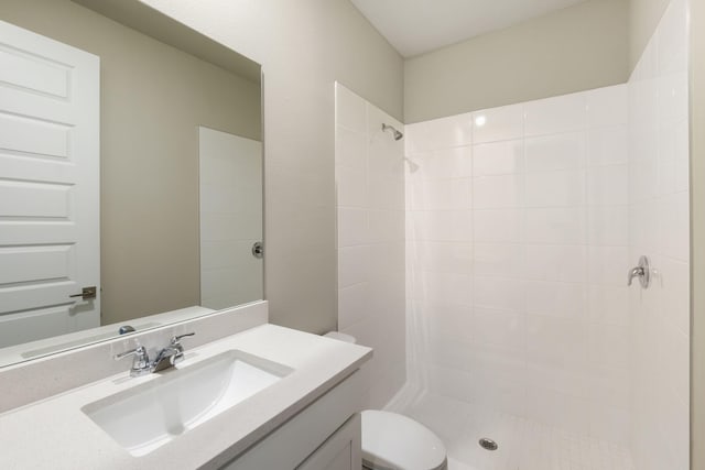 full bathroom with a tile shower, toilet, and vanity