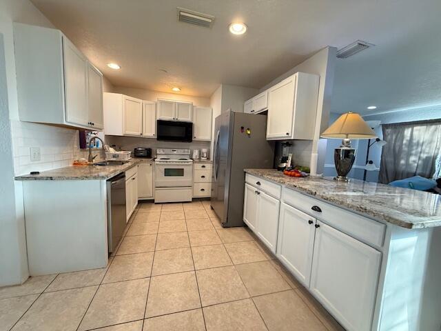 kitchen with stainless steel appliances, light tile patterned flooring, a sink, and visible vents