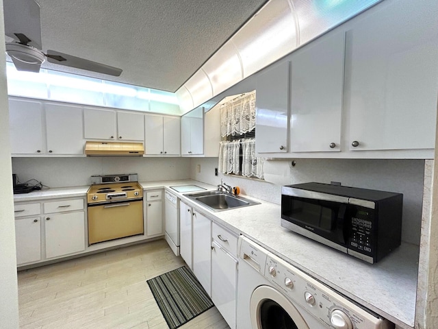 kitchen featuring range with electric stovetop, washer / clothes dryer, white dishwasher, a sink, and under cabinet range hood