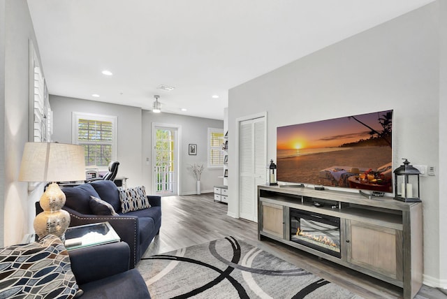 living room featuring visible vents, baseboards, wood finished floors, and recessed lighting