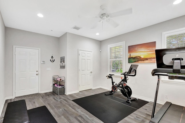 exercise room with wood finished floors, visible vents, and baseboards