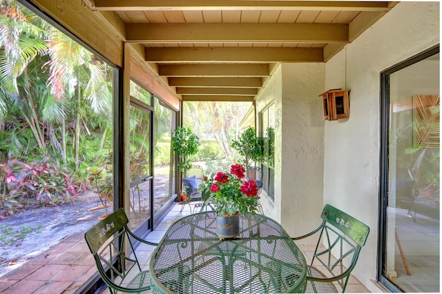 unfurnished sunroom featuring beamed ceiling