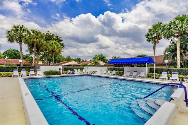 community pool with a patio area and fence