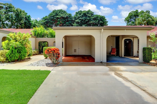 mediterranean / spanish home with driveway, an attached carport, and stucco siding