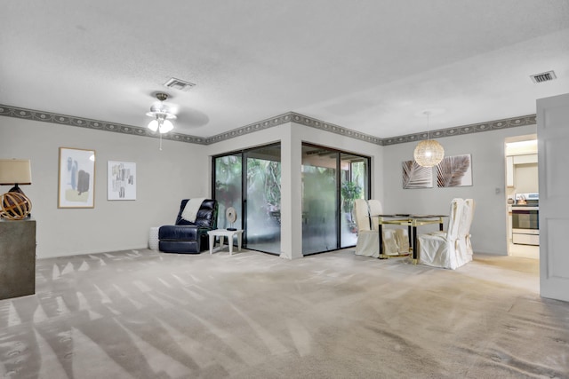 living area with a ceiling fan, carpet, visible vents, and a textured ceiling