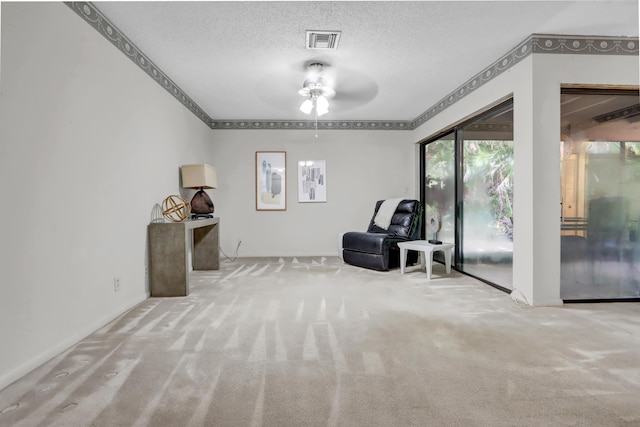 unfurnished room featuring carpet, visible vents, ceiling fan, and a textured ceiling