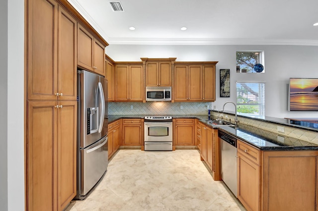 kitchen featuring visible vents, brown cabinets, a peninsula, stainless steel appliances, and a sink