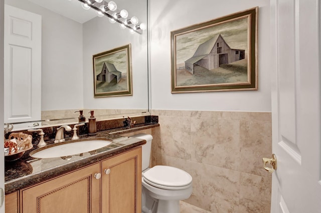 bathroom with a wainscoted wall, tile walls, toilet, and vanity