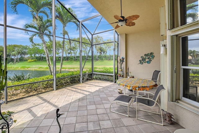 sunroom with ceiling fan and a water view