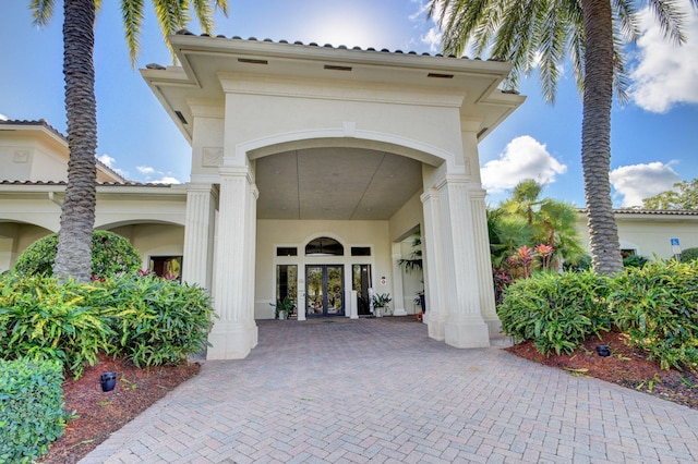 property entrance featuring stucco siding, a tile roof, and french doors