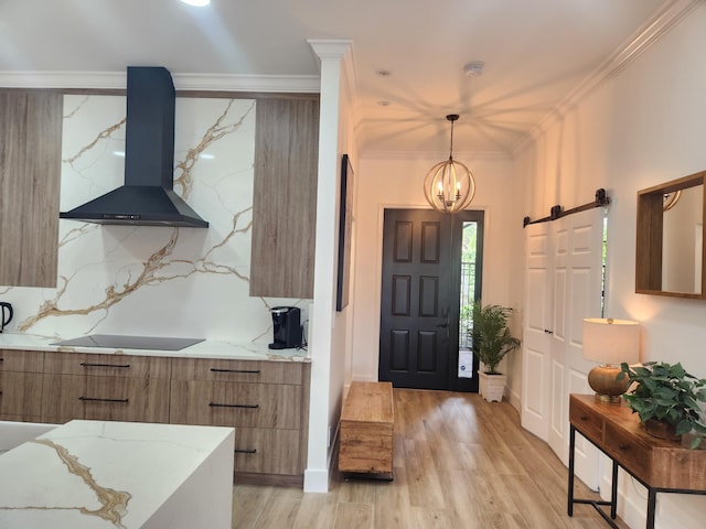 entryway featuring an inviting chandelier, ornamental molding, a barn door, light wood-type flooring, and baseboards