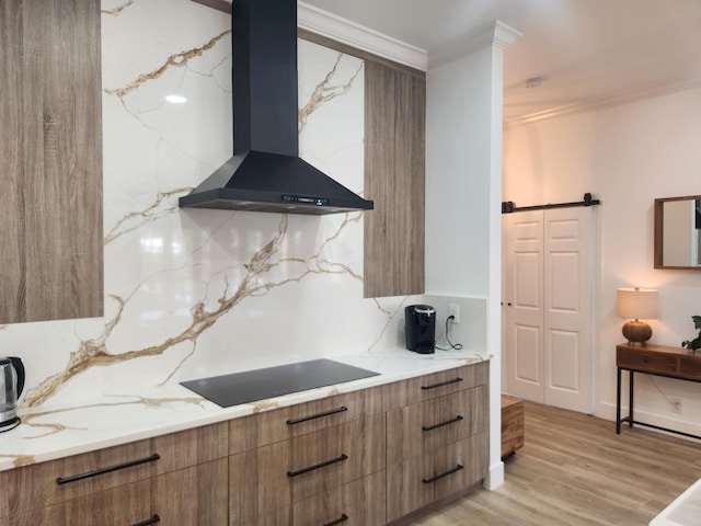 kitchen featuring wall chimney range hood, modern cabinets, black electric cooktop, and brown cabinetry