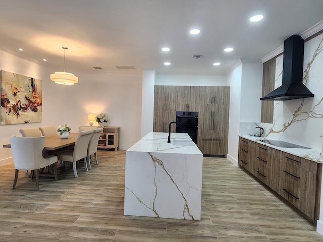 kitchen with black appliances, wall chimney range hood, modern cabinets, and decorative backsplash