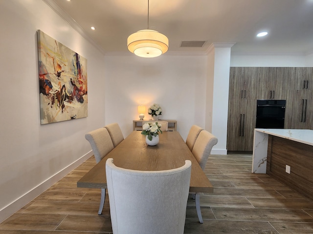 dining room with baseboards, wood finish floors, visible vents, and crown molding