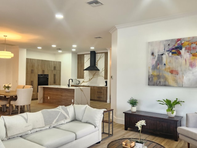 living room featuring recessed lighting, visible vents, baseboards, light wood-style floors, and ornamental molding