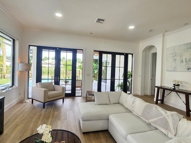 living area with light wood-style flooring, visible vents, arched walkways, and french doors