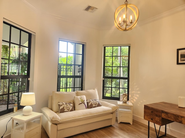 living area featuring visible vents, baseboards, ornamental molding, light wood finished floors, and an inviting chandelier