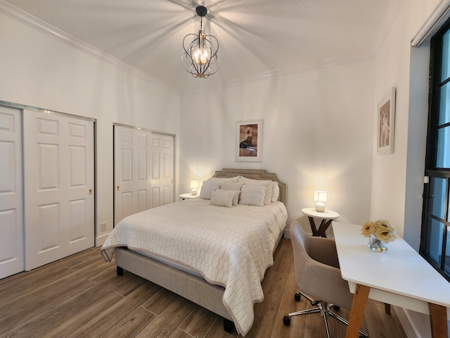 bedroom with a chandelier, multiple closets, wood finished floors, and crown molding