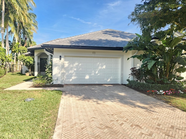 ranch-style home with an attached garage, a front yard, decorative driveway, and stucco siding