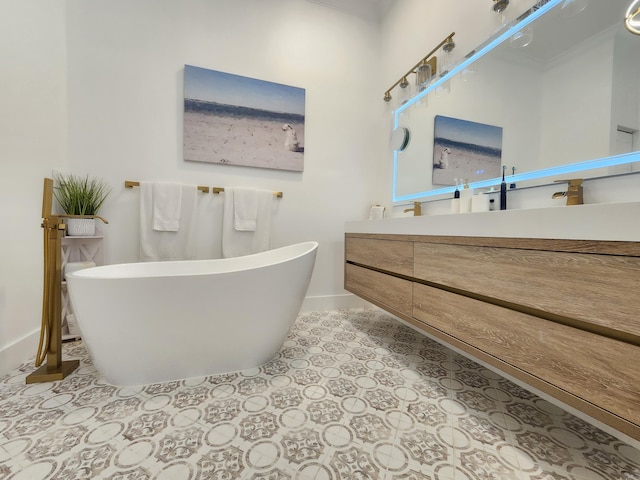 bathroom with a freestanding bath, vanity, baseboards, and tile patterned floors