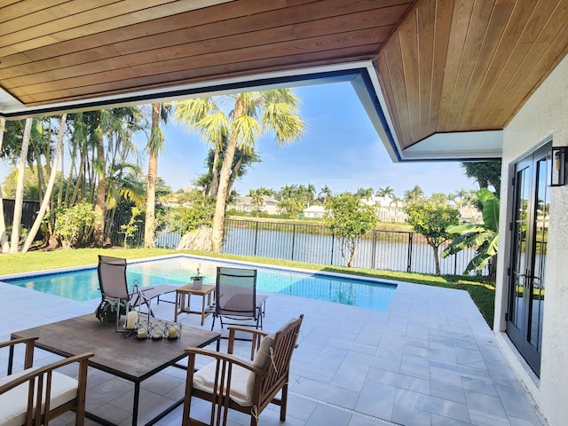 view of pool featuring a water view, a patio area, a fenced backyard, and french doors