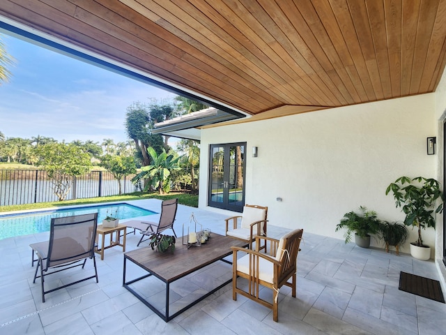 view of patio with a water view, fence, a fenced in pool, and french doors