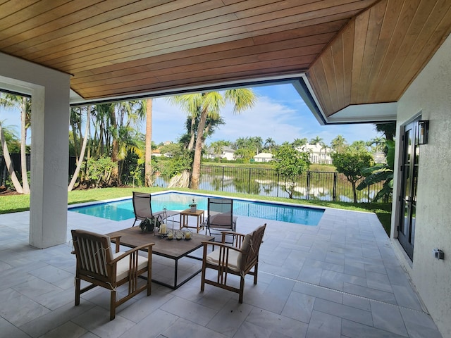 view of swimming pool featuring a water view, a fenced backyard, a fenced in pool, and a patio