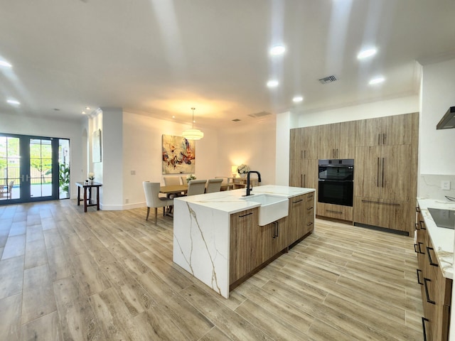 kitchen with visible vents, modern cabinets, french doors, light wood-style floors, and a sink