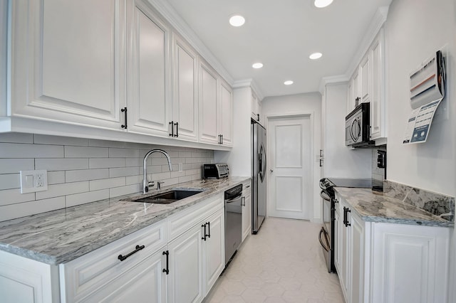 kitchen with stainless steel appliances, a sink, white cabinetry, light stone countertops, and tasteful backsplash