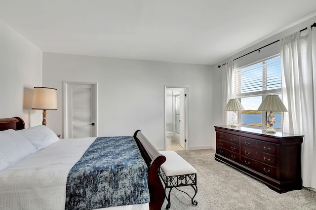 bedroom with ensuite bath, baseboards, and light colored carpet