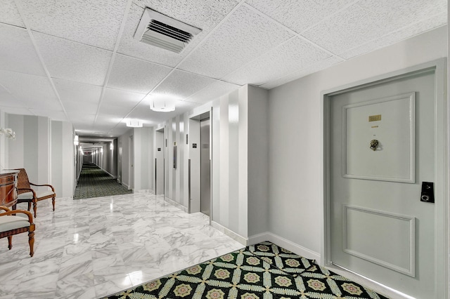 hallway with baseboards, visible vents, elevator, marble finish floor, and a paneled ceiling