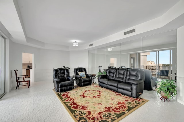 living area with a tray ceiling and visible vents