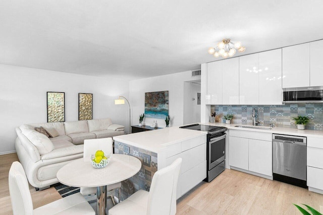 kitchen featuring appliances with stainless steel finishes, open floor plan, a sink, modern cabinets, and a peninsula