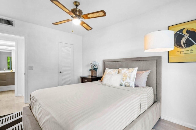 bedroom with a ceiling fan, visible vents, baseboards, and wood finished floors