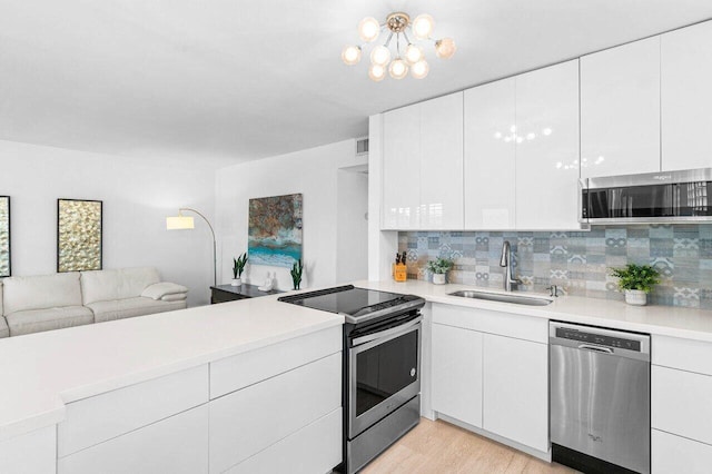 kitchen with a sink, white cabinets, open floor plan, light countertops, and appliances with stainless steel finishes