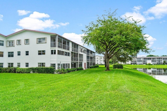 view of property's community with a water view and a lawn