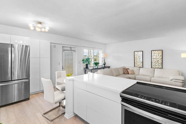 kitchen with stainless steel appliances, light wood-style flooring, open floor plan, white cabinets, and modern cabinets