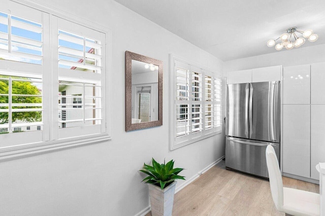 kitchen featuring light wood-style floors, baseboards, white cabinets, and freestanding refrigerator