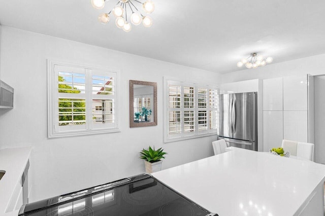 kitchen with a chandelier, white cabinetry, light countertops, range, and freestanding refrigerator