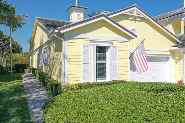 view of side of home featuring an attached garage and stucco siding