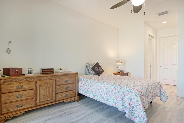 bedroom featuring light wood finished floors, visible vents, and a ceiling fan