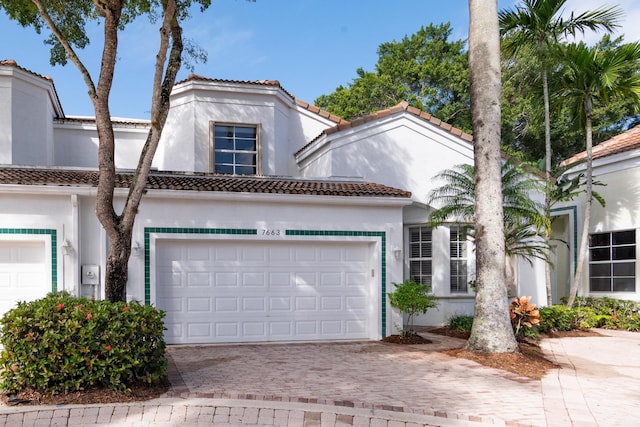 view of front of property featuring a garage, a tiled roof, decorative driveway, and stucco siding