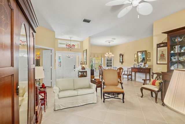 living area featuring light tile patterned floors, plenty of natural light, visible vents, and ceiling fan with notable chandelier