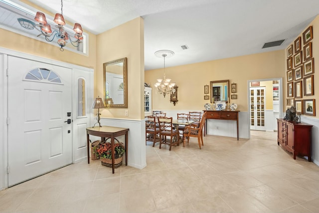 entryway with light tile patterned floors, visible vents, and a notable chandelier