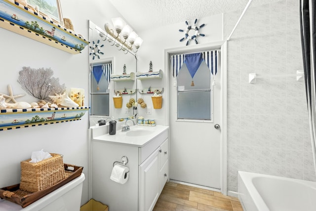 full bathroom with a textured ceiling,  shower combination, vanity, and toilet