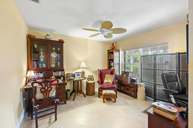 sitting room with ceiling fan, a textured ceiling, baseboards, and light tile patterned floors