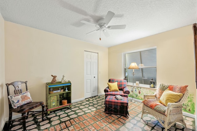 sitting room featuring baseboards, a ceiling fan, and a textured ceiling